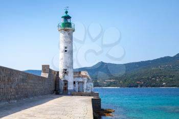 White stone lighthouse tower on the pier. Entrance to Propriano port, Corsica island, France