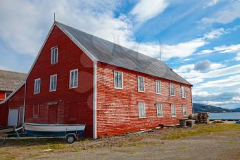Red wooden fishing barn with small boat. Rorvik town, Norway
