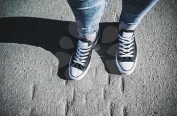 Black and white new sneakers, teenager feet stand on urban pavement