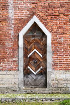 Dark wooden door in red brick wall, Gothic Revival architecture style. Background texture