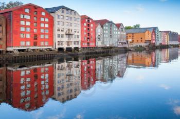 Colorful wooden living houses stand in a row along the river coast. Trondheim, Norway