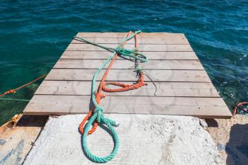 Colorful nautical ropes lay on small wooden pier. Zakynthos, Greece