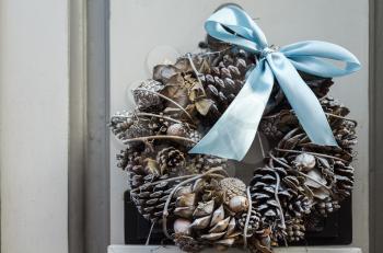 Decorative wreath of twigs with cones and a blue bow knot