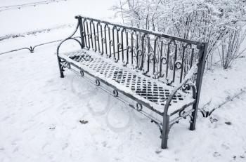 Outdoor metal bench covered with snow in winter park. Saint-Petersburg, Russia