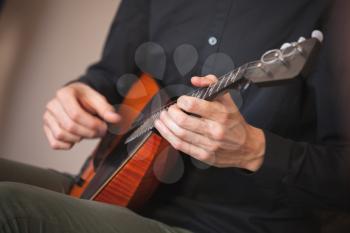 Russian folk music background. Hands of a man playing balalaika, close-up photo with selective focus