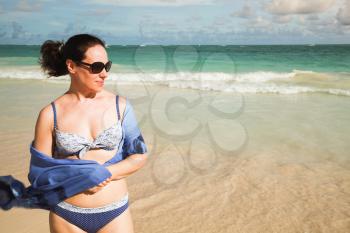 Young beautiful Caucasian woman in sunglasses with blue pareo on the beach. Outdoor portrait