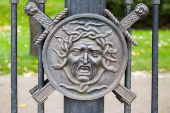 Medusa face. In Greek mythology it was a monster, a Gorgon, winged human female with living venomous snakes in place of hair. Decorative fence of Summer Garden, built in 1825, St.Petersburg, Russia