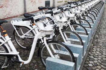 White city bicycles for rent stand in a row on a cobbled street of Copenhagen, Denmark