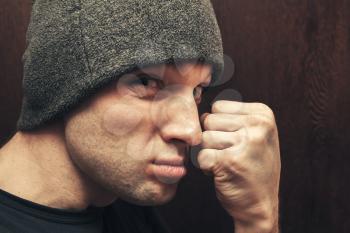 Young aggressive Caucasian man shows fist. Closeup studio face portrait, selective focus