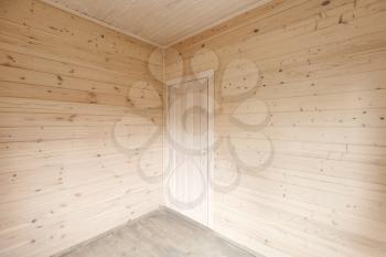 Empty interior fragment, wooden walls and white door in the corner