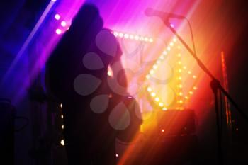 Bright colorful blurred rock music abstract background, bass guitar player on a stage