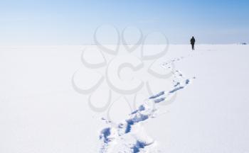 Footsteps of lonely person walking on frozen sea covered with snow. Russian winter