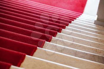 Red carpet lays on white marble stairs going down