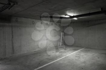 Abstract empty parking lot interior background with dark gray concrete walls and white ceiling lights