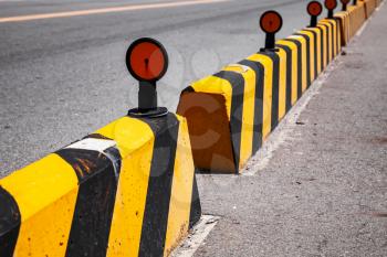 Concrete blocks with caution pattern, road fence with reflectors