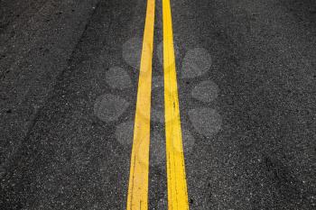 Yellow double dividing lines, highway road marking on dark asphalt