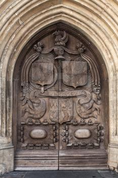 Old wooden door with carving, entrance of Abbey Church of St.Peter and St.Paul, commonly known as Bath Abbey. Anglican parish church and former Benedictine monastery in Bath, Somerset, UK