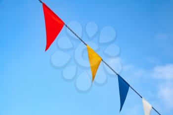 Colorful triangle flags on rope over blue cloudy sky background
