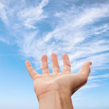Right male hand with empty place for holding something, on blue sky background. Photo with selective focus