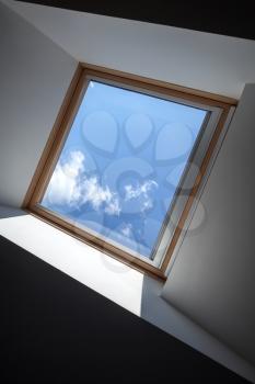 Modern ceiling fragment with window and blue sky behind it