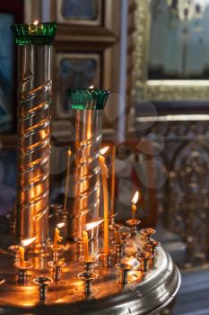 Candles are lit in a dark Orthodox Church