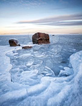 Vertical winter landscape with ice and stones on frozen Baltic Sea
