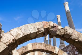 Ancient columns and arches over blue sky background, fragment of ruined roman temple in Smyrna. Izmir, Turkey