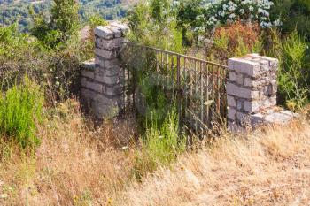 Old abandoned locked stone gate in summer day. Corsica, France
