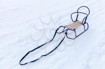 Small metal sled with wooden seat standing in the snow