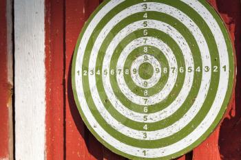 Old darts target hanging on red wooden wall