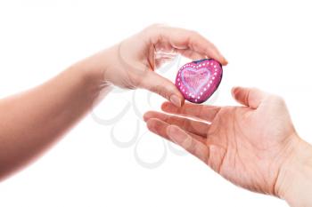 Pink painted handmade heart shaped stone as a gift in woman's hand isolated on white