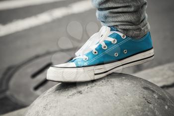 Blue sneaker, teenager foot in urban environment. Closeup photo with selective focus and shallow DOF