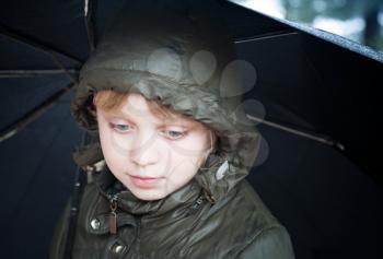Portrait of a little blond girl with umbrella in a casual jacket with the hood