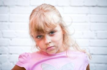 Portrait of a little blond beautiful Russian girl above white brick wall background