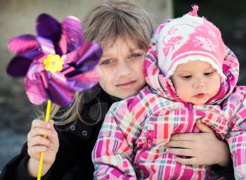 Two Little sisters outdoor portrait with pinwheel toy