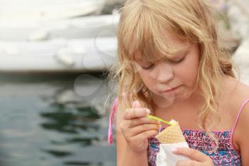 Little blond girl eats ice cream. Outdoor summer portrait
