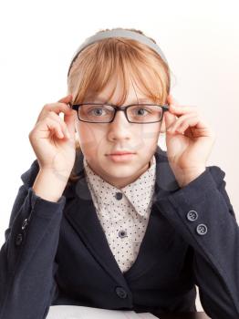 Little blond schoolgirl with glasses, closeup studio portrait