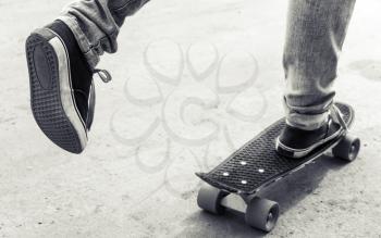 Feet of a skateboarder in jeans and gumshoes, monochrome retro stylized photo