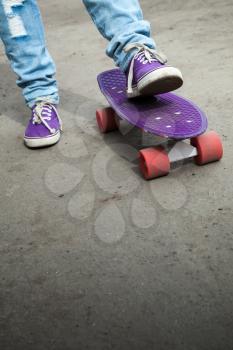 Feet in a blue jeans and gumshoes and skateboard, selective focus with shallow DOF