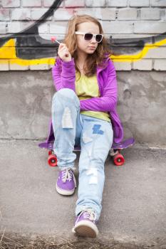 Blond teenage girl with lollipop, vertical urban outdoor portrait