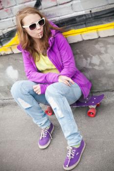 Blond teenage girl with lollipop, vertical urban portrait