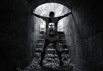 Infinity inner world concept, young man stands in dark stone tunnel with glowing end