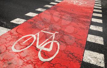 Red bicycle road marking on urban asphalt road crossing 