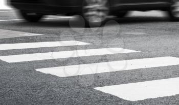 Pedestrian crossing road marking and fast moving car, photo with selective focus and shallow DOF