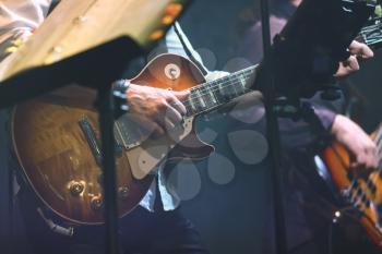 Old style rock music background, guitar player on a stage with colorful illumination, selective focus