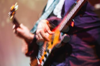 Colorful blurred rock music background, guitar players on a stage, motion blur effect