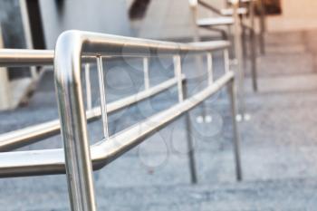 Shining urban metal handrails on a stairway, closeup photo with selective focus