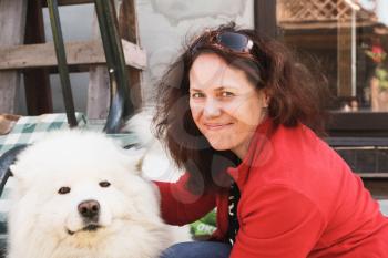 Happy young Caucasian woman with white fluffy Samoyed dog