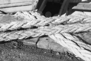 Nautical ropes used for mooring operations lay on the pier, closeup black and white photo with selective focus