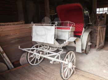 Vintage white coach with red saloon stands in rural garage